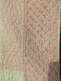 pink and white quilt with embroidered names