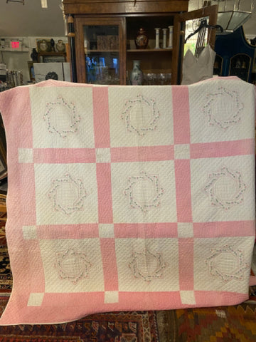 pink and white quilt with embroidered names