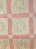 pink and white quilt with embroidered names