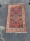 red rug with ivory border and blue and peach medallions