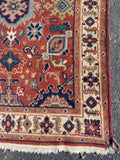 red rug with ivory border and blue and peach medallions