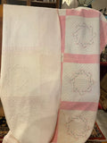 pink and white quilt with embroidered names