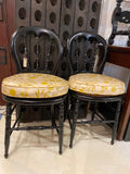 pair of black spindle chairs with seat cushions